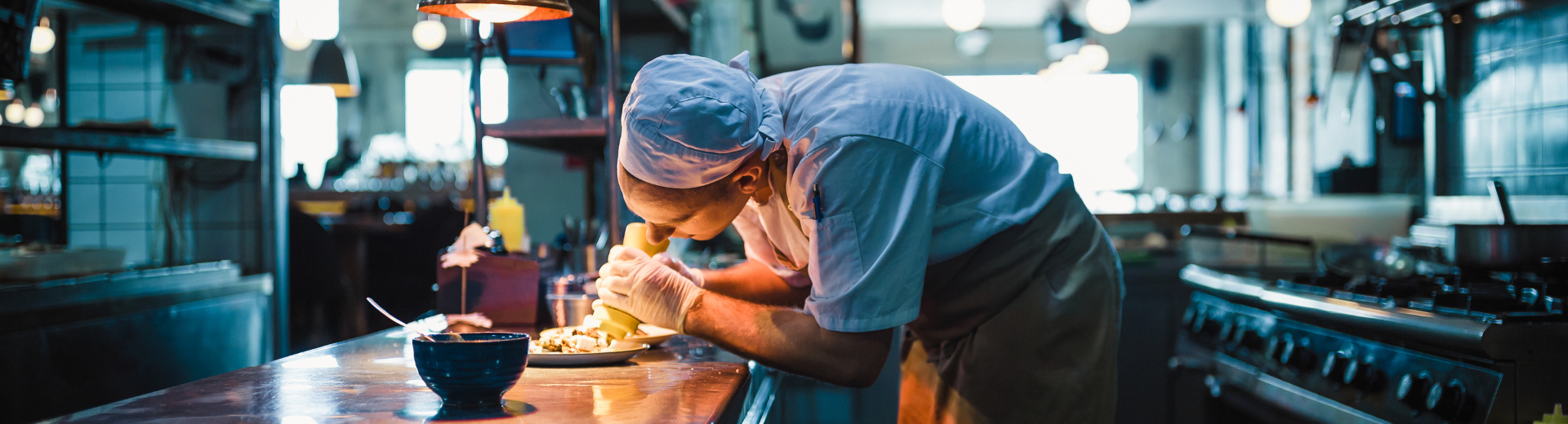 Restaurant chef garnishing a plate of food.