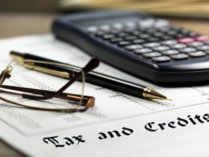 Tax and Credits with pen, glasses, and calculator