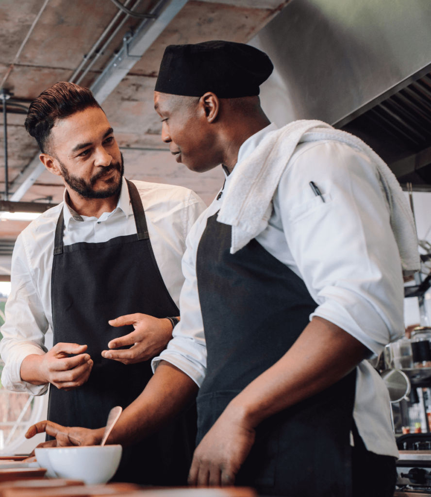 2 male chefs in kitchen plating food