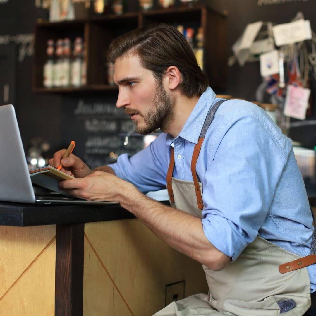 Restaurant operator reviewing report on laptop