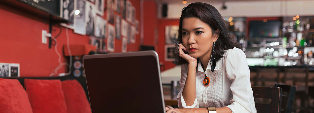 Woman looking at laptop in restaurant.