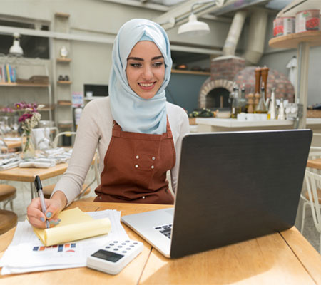 Woman taking notes on laptop in restaurant