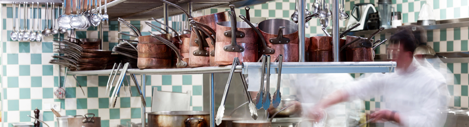 Copper pots and pans in busy restaurant kitchen.