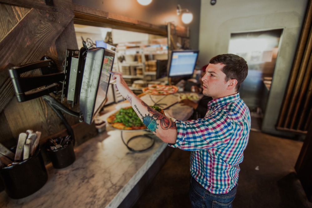 Restaurant BOH employee working on kitchen display system (KDS).